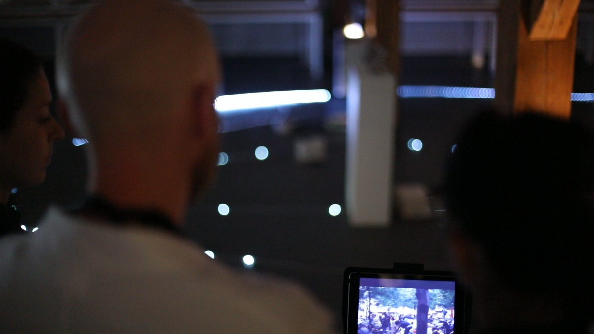 Participants gather around a dimly lit loop of LED markers in the exhibition hall, peering at a tablet that streams real-time projections of future energy scenariosāevoking the immersive, game-like environment of Escaping the Strange Loop.